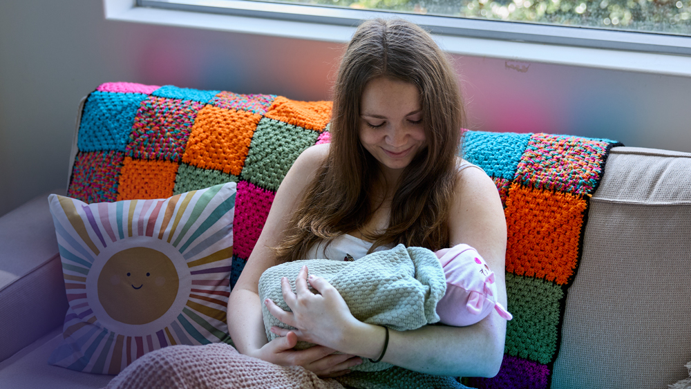 Mum and baby sitting on the couch in their home with bright decor